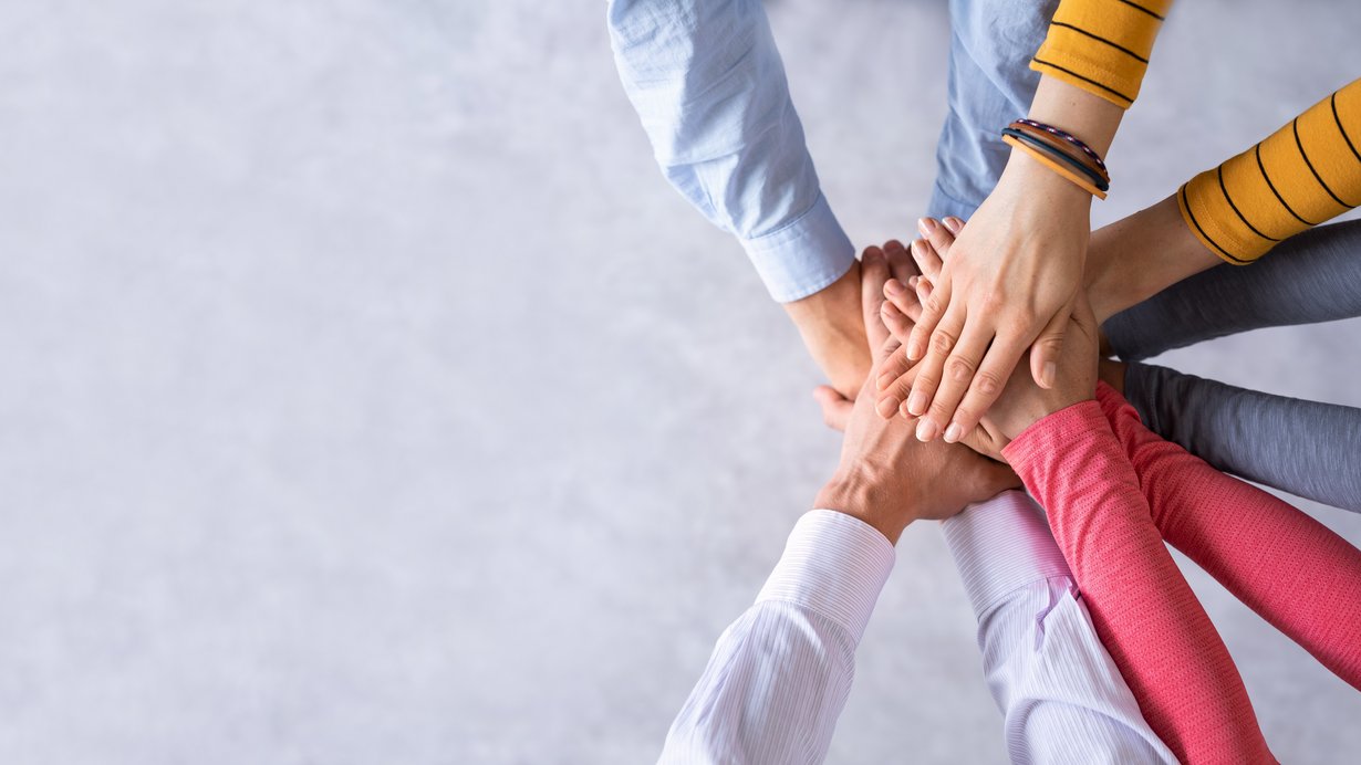 Mehrere Hände treffen sich in der Mitte eines Kreises