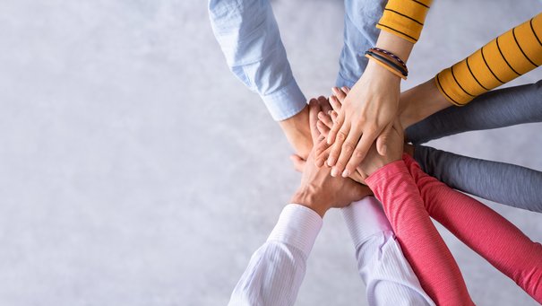 Mehrere Hände treffen sich in der Mitte eines Kreises