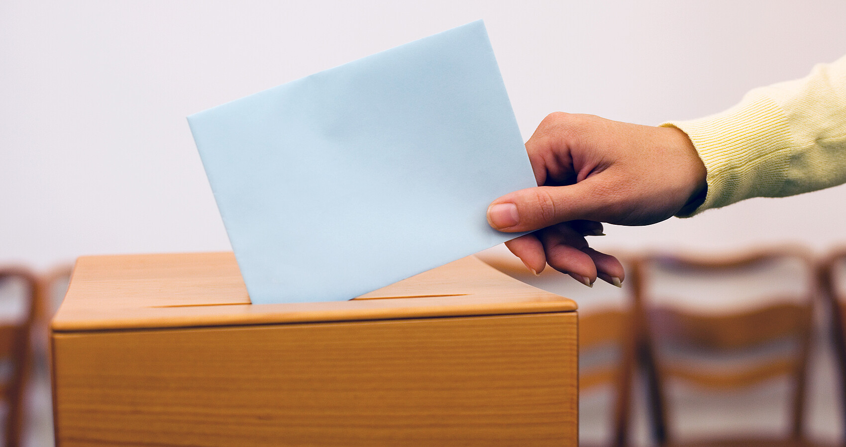 Hand wirft Zettel in Wahlurne