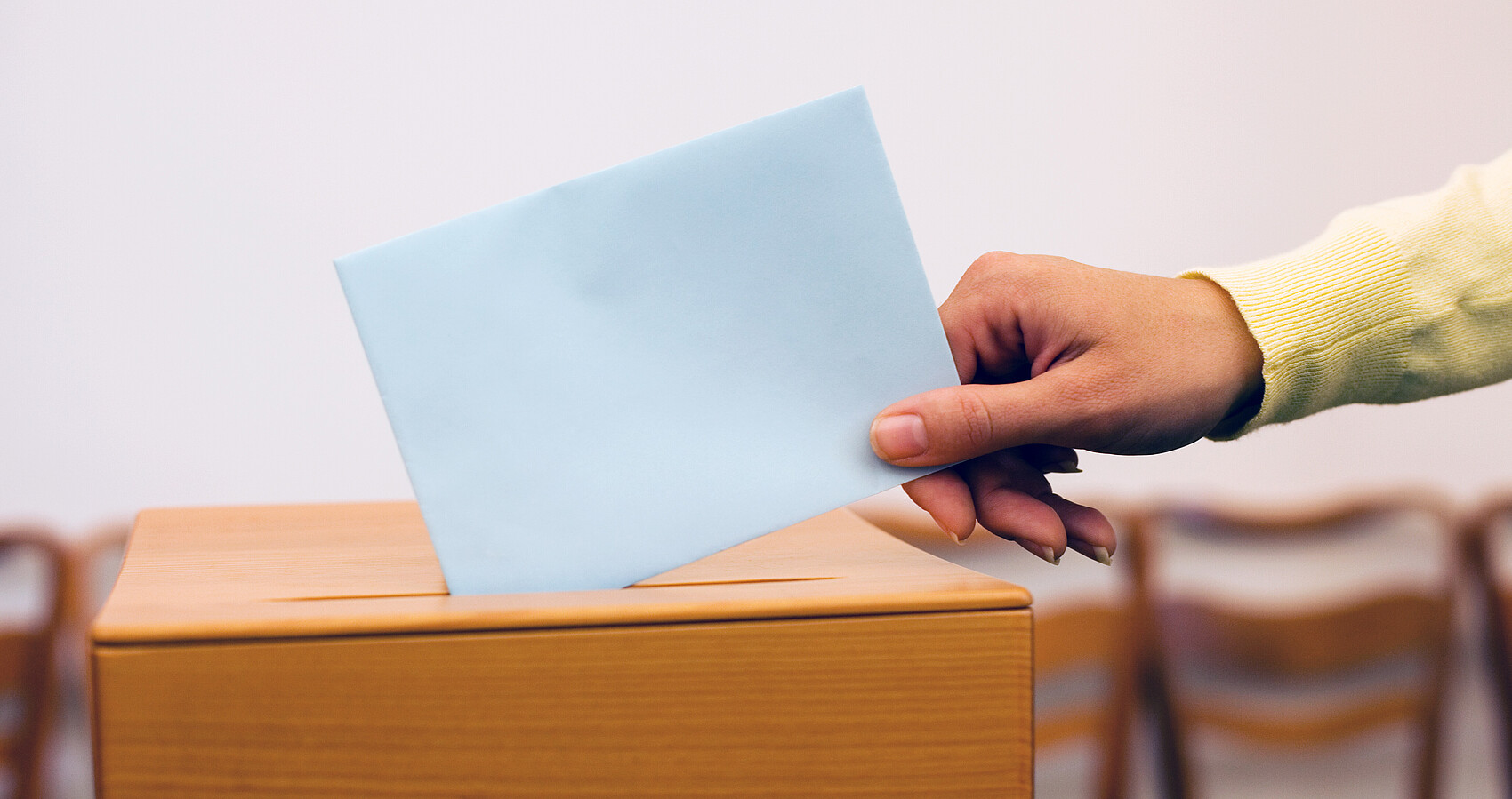 Hand wirft Zettel in Wahlurne