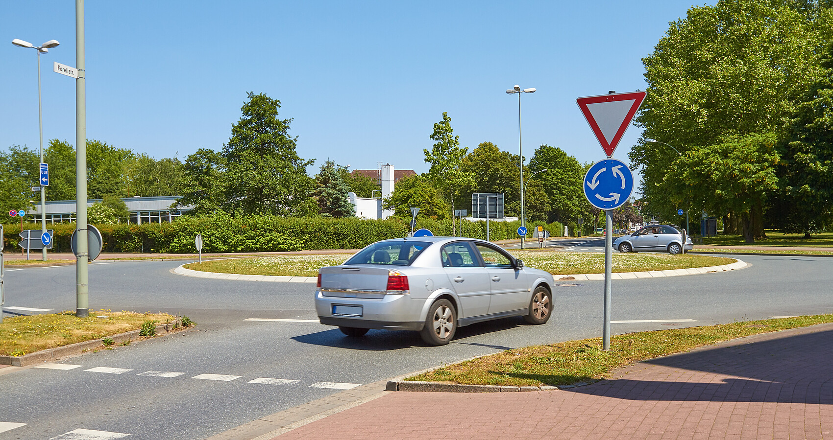 Ein graues Auto fährt in einen Kreisverkehr