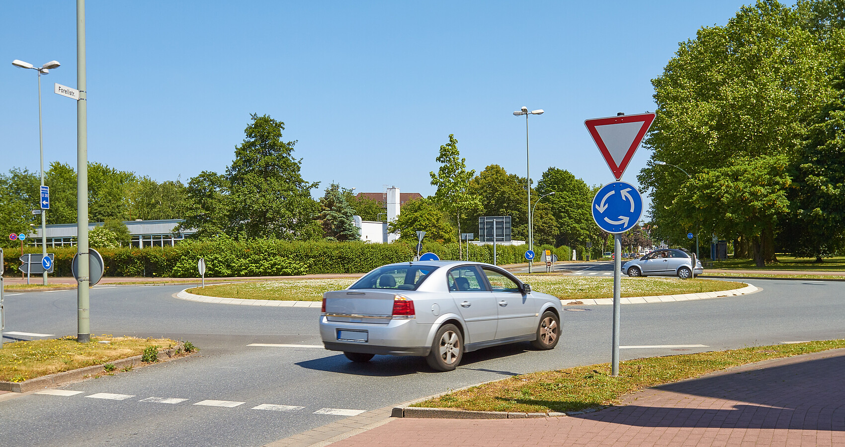 Ein graues Auto fährt in einen Kreisverkehr