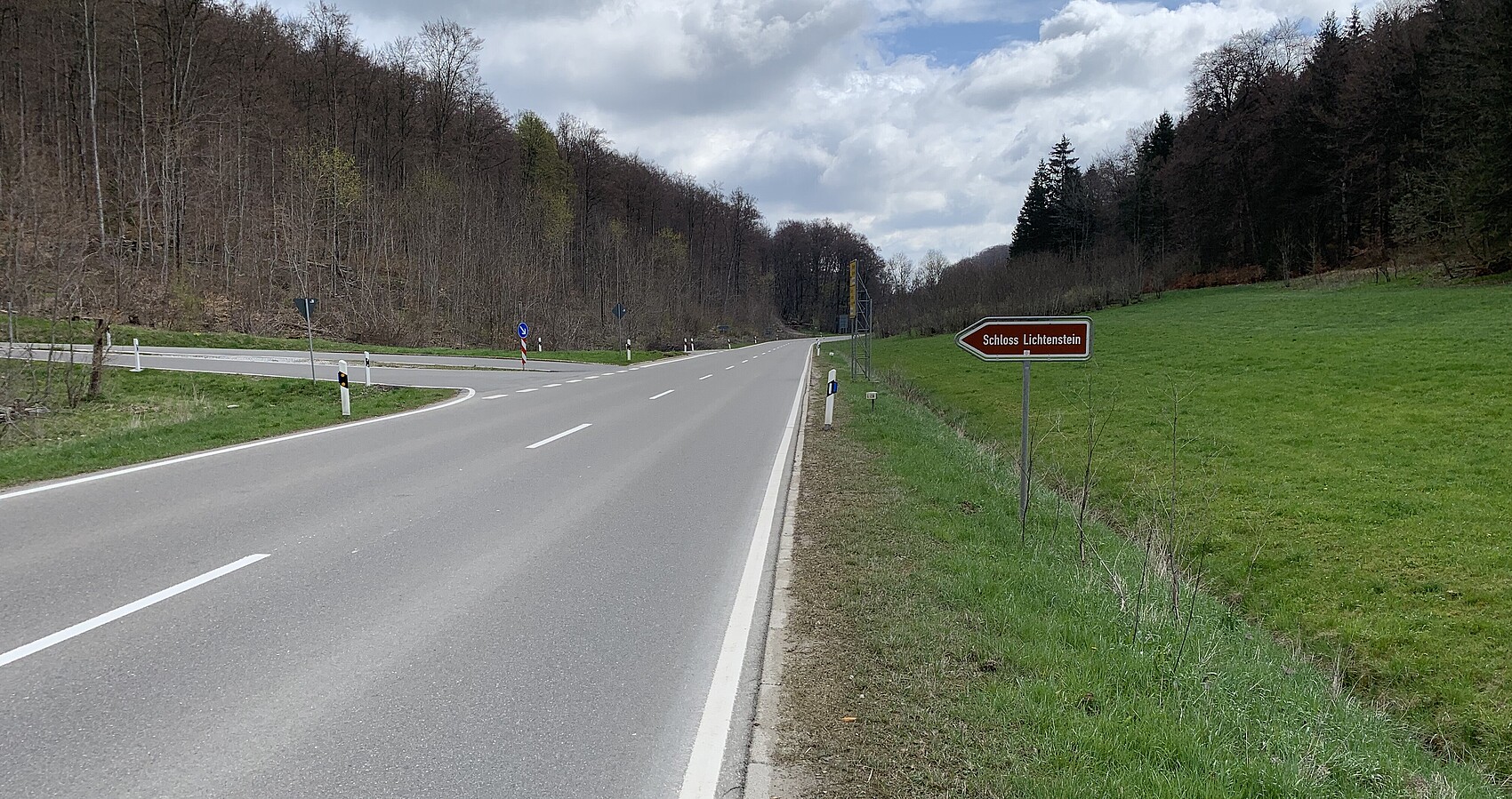 Das Foto zeigt die Abfahrt von der L 230 zum Schloss Lichtenstein; links und rechts Wiesen und Wald