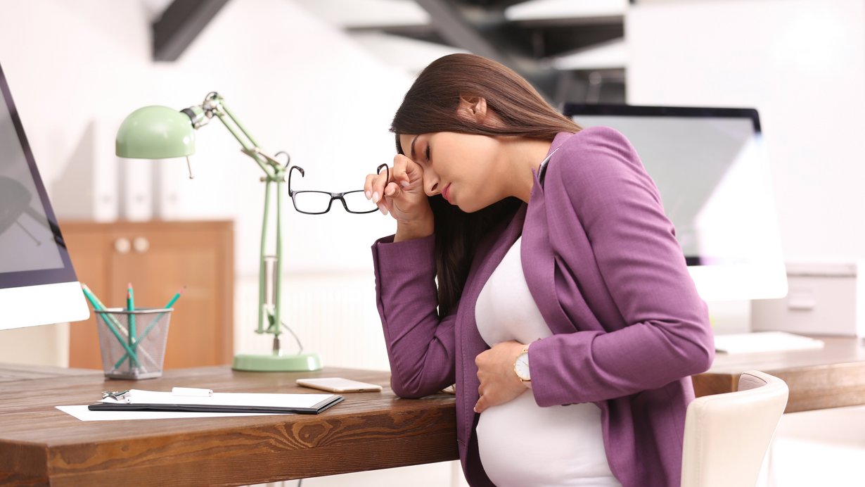 Schwangere Frau leidet unter Schmerzen an ihrem Arbeitsplatz