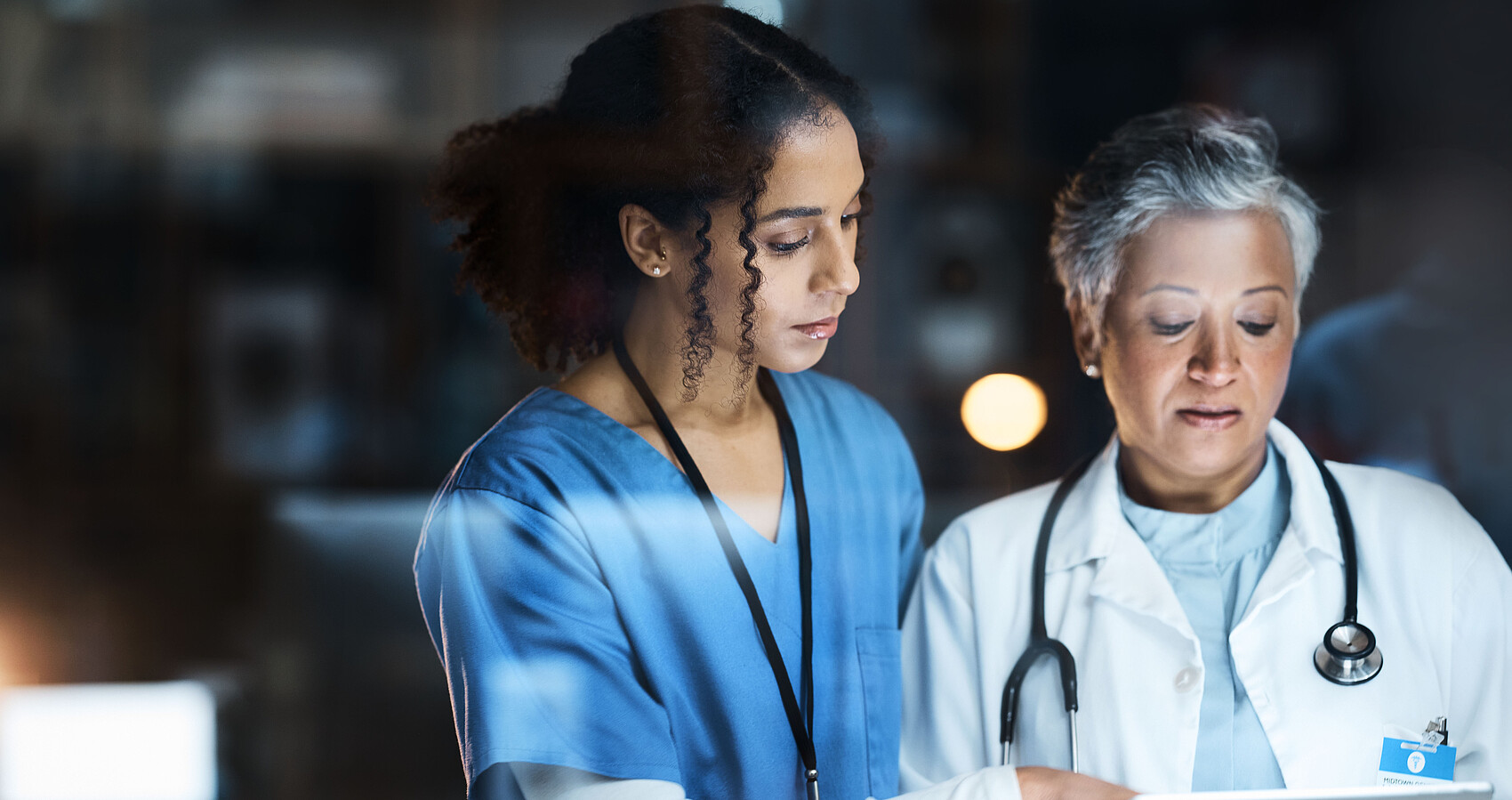 Eine Krankenschwester und eine Ärztin schauen gemeinsam auf ein Tablet