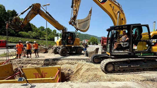 Zwei Bagger, die an einem Graben durch eine Straße arbeiten