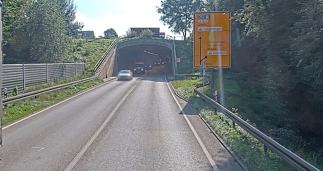 Blick auf einen Tunnel auf der B 31 zwischen Eriskirch und Kressbronn. Straßenschilder und Autos, die aus dem Tunnel kommen