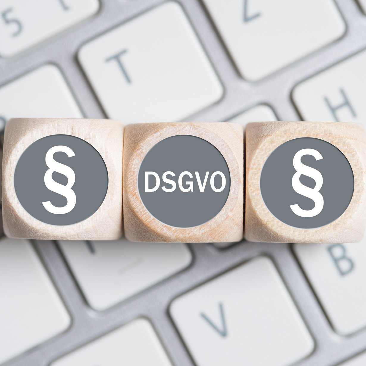 Würfel mit Paragraph Symbolen und Abkürzung DSGVO auf einer Tastatur