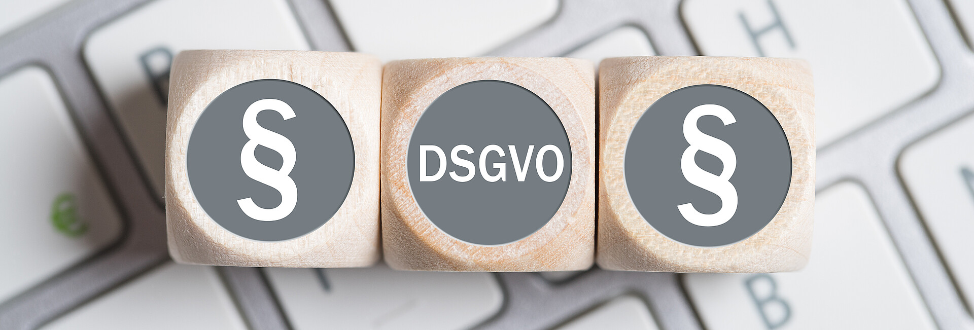 Würfel mit Paragraph Symbolen und Abkürzung DSGVO auf einer Tastatur