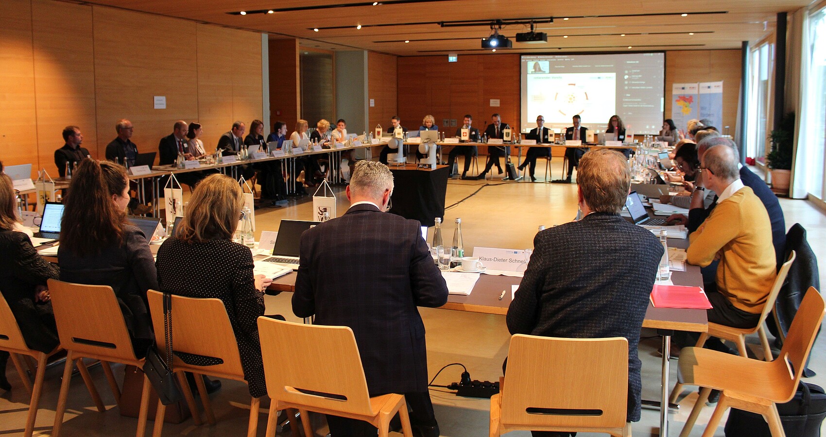 Das Bild zeigt die Teilnehmer der Konstituierenden Sitzung des Interreg-Begleitausschusses in einem Sitzungssaal an Tischen