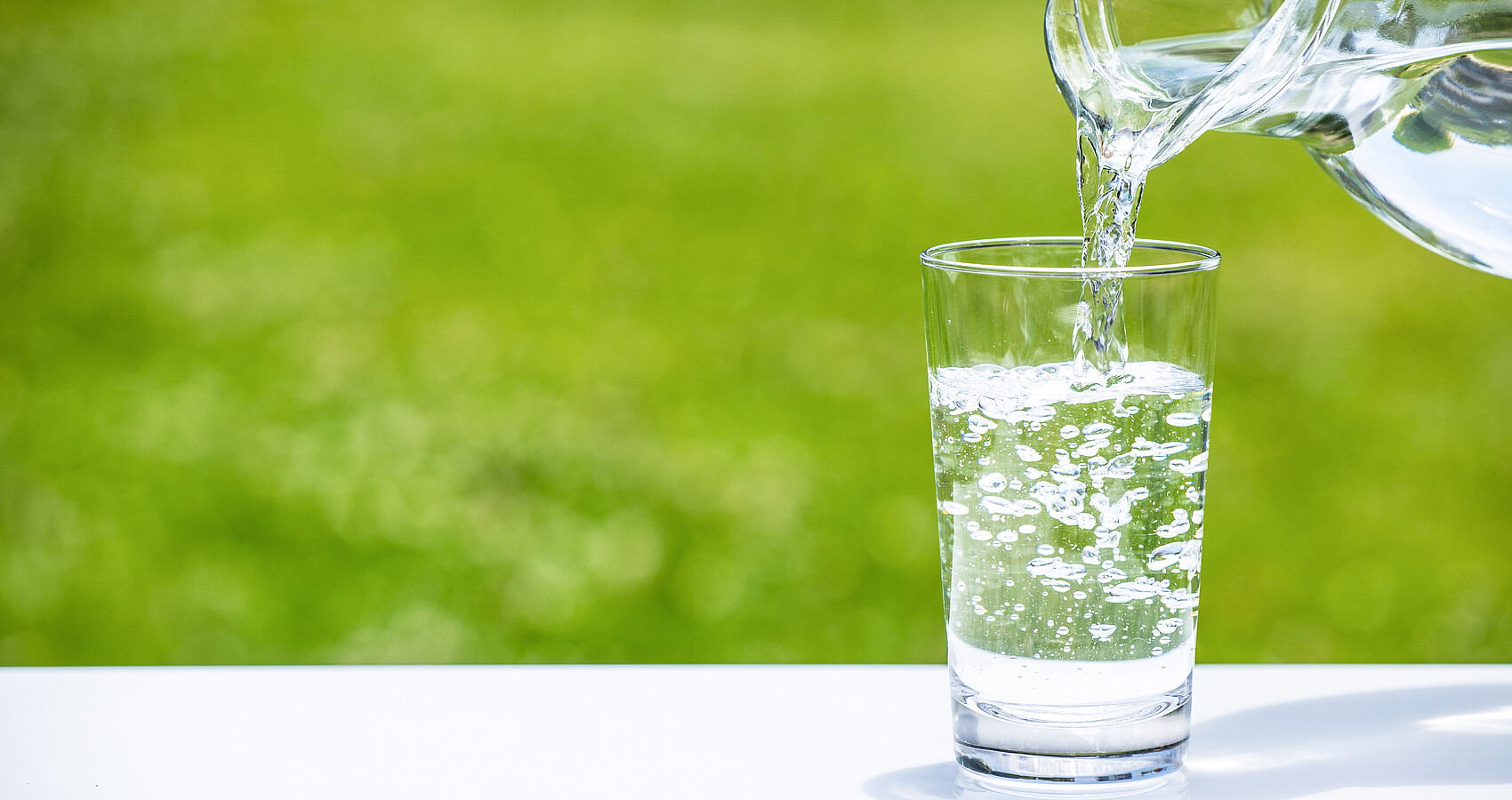 Aus einer Karaffe Wasser wird Wasser in ein Wasserglas gefüllt