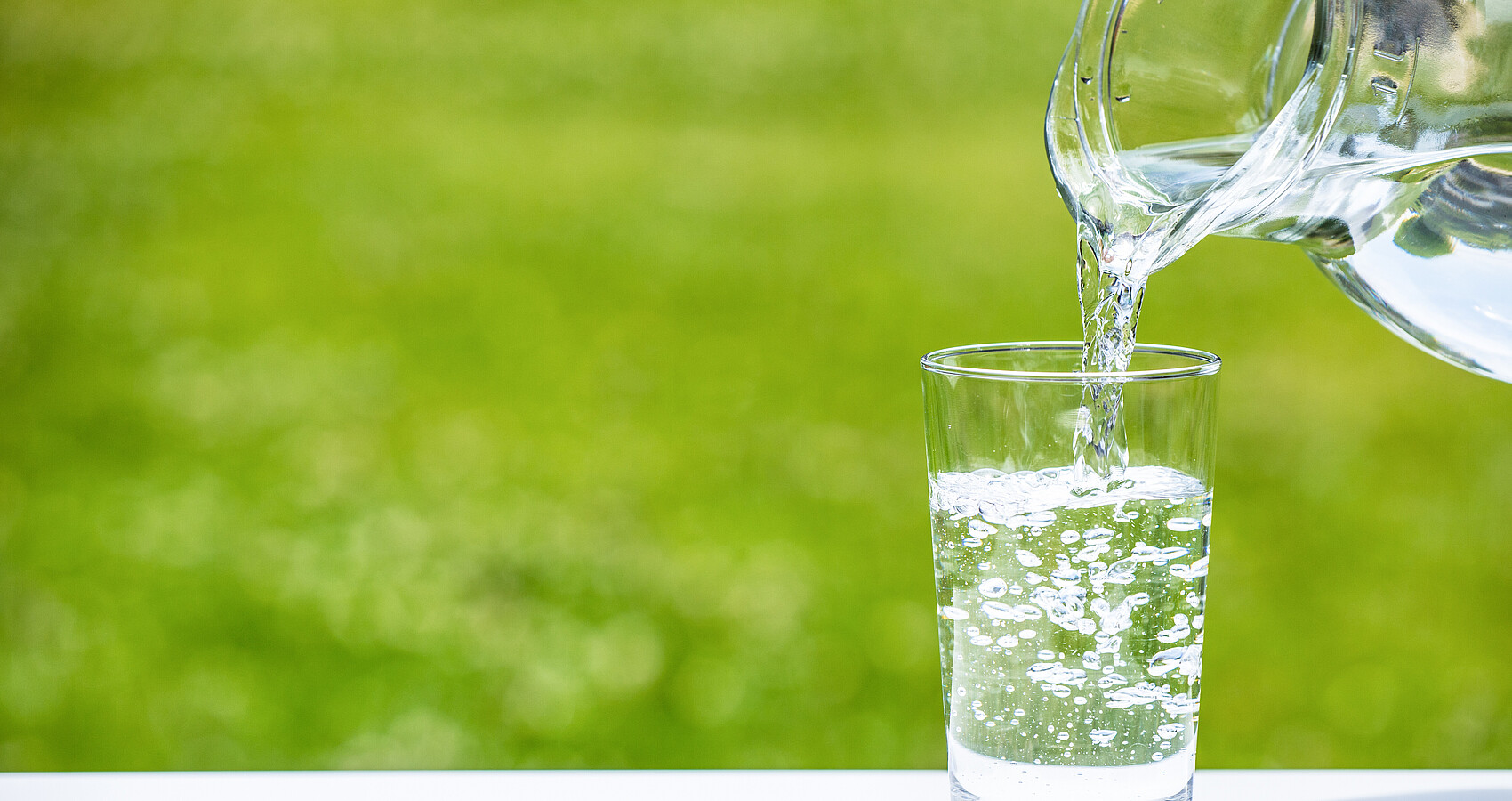 Aus einer Karaffe Wasser wird Wasser in ein Wasserglas gefüllt