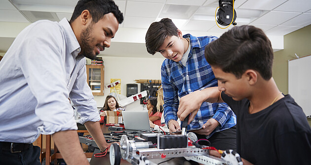 Lehrer mit Schülern, die ein Roboter-Fahrzeug im naturwissenschaftlichem Unterricht bauen