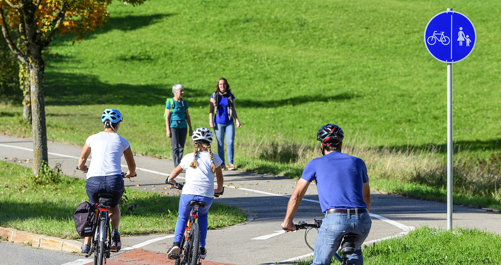 Radfahrer befahren einen Übergang von der Straße auf einen kombinierten Rad- und Fußweg
