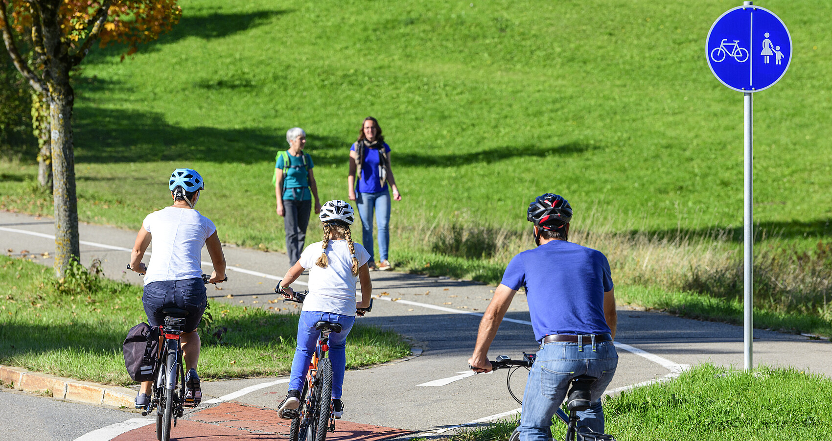 Radfahrer befahren einen Übergang von der Straße auf einen kombinierten Rad- und Fußweg