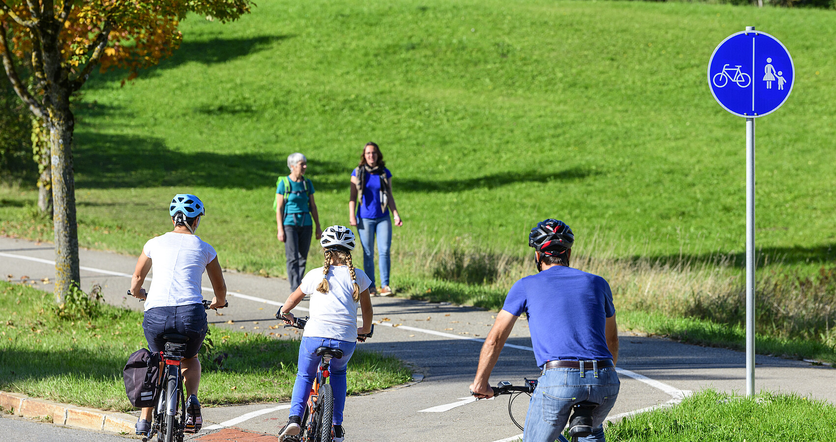 Radfahrer befahren einen Übergang von der Straße auf einen kombinierten Rad- und Fußweg