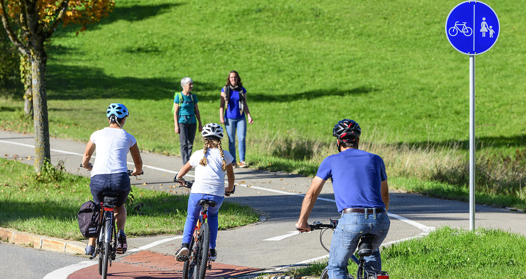 Radfahrer befahren einen Übergang von der Straße auf einen kombinierten Rad- und Fußweg