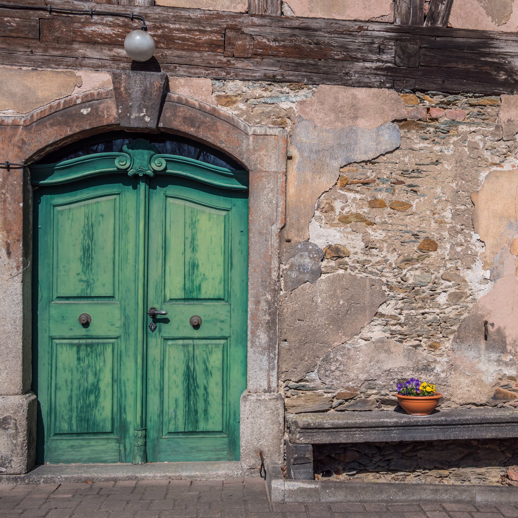 Hauseingang mit grüner, alter Haustüre und Fenster mit grünen Holzläden
