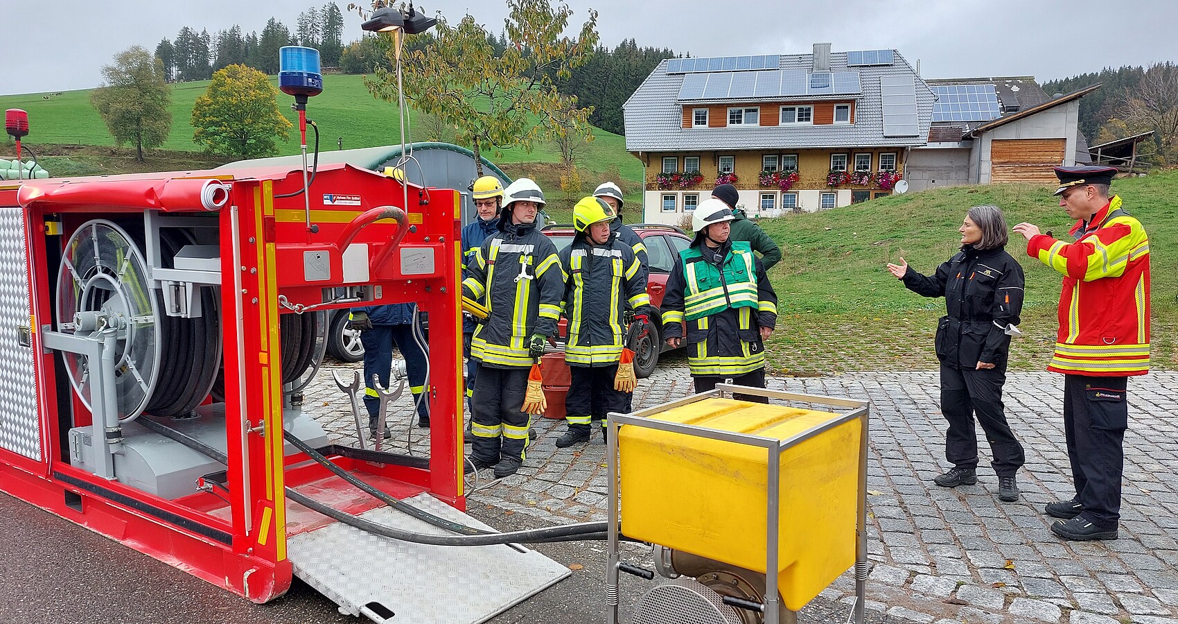 Regierungspräsidentin Schäfer beobachtet Feuerwehrleute beim Aufbau einer Wasserleitung.