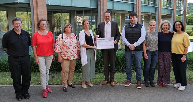 Das Foto zeigt 3 Männer und 6 Frauen vor dem Gebäude des Regierungspräsidium Tübingen; Herr Tappeser hält den Scheck in den Händen