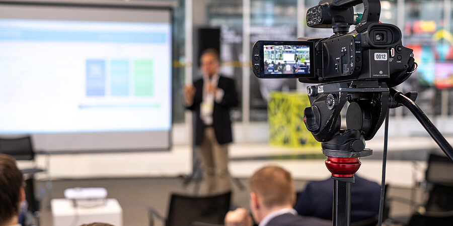 Eine Kamera filmt einen Referente in einer Veranstaltung