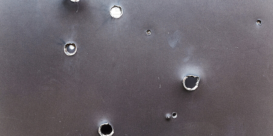 graue Stahlplatte mit Einschusslöchern 