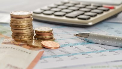 Geld und ein Taschenrechner liegen zusammen mit einem Kulli auf einem Tisch