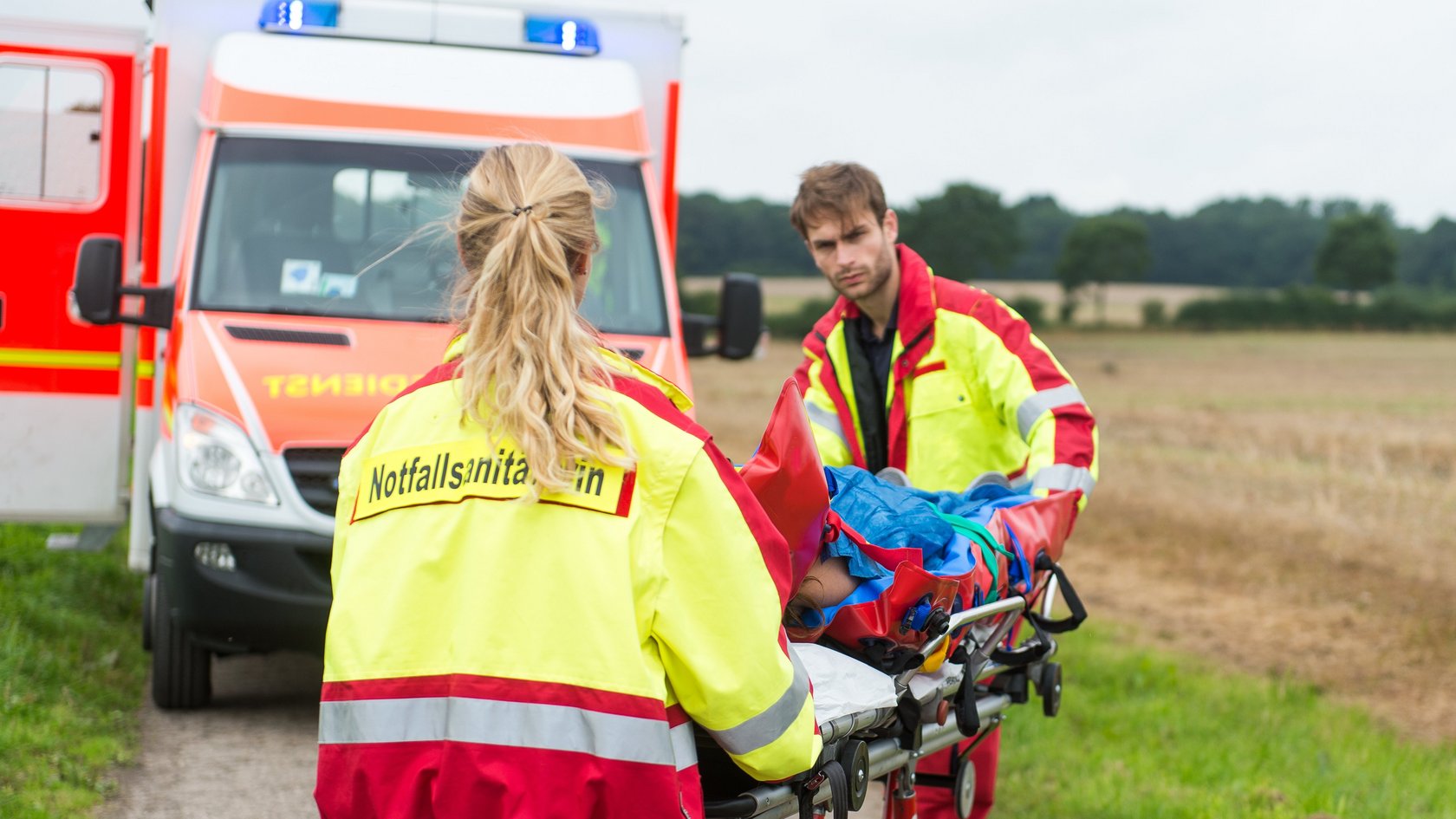 Junge Frau wird von der Rettungswagenbesatzung versorgt und in den Rettungswagen gebracht