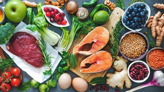 Auf dem Bild werden verschiedensteEine bunte Auswahl an Gemüse, Beeren, Fleisch, Bohnen, Getreide und Nüsse abgebildet