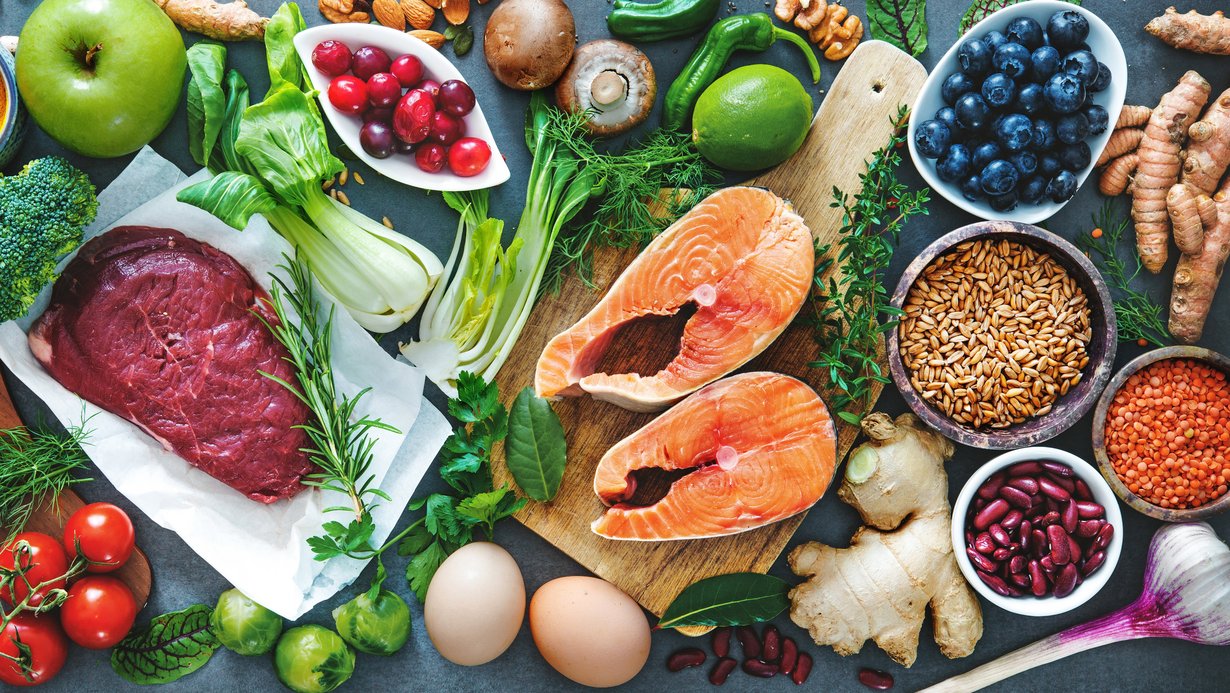 Auf dem Bild werden verschiedensteEine bunte Auswahl an Gemüse, Beeren, Fleisch, Bohnen, Getreide und Nüsse abgebildet