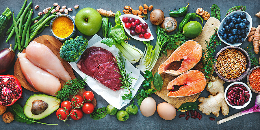 Auf dem Bild werden verschiedensteEine bunte Auswahl an Gemüse, Beeren, Fleisch, Bohnen, Getreide und Nüsse abgebildet