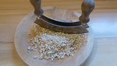 Zerkleinern der Erdnüsse auf einem weißen Teller mit einem Wiegemesser