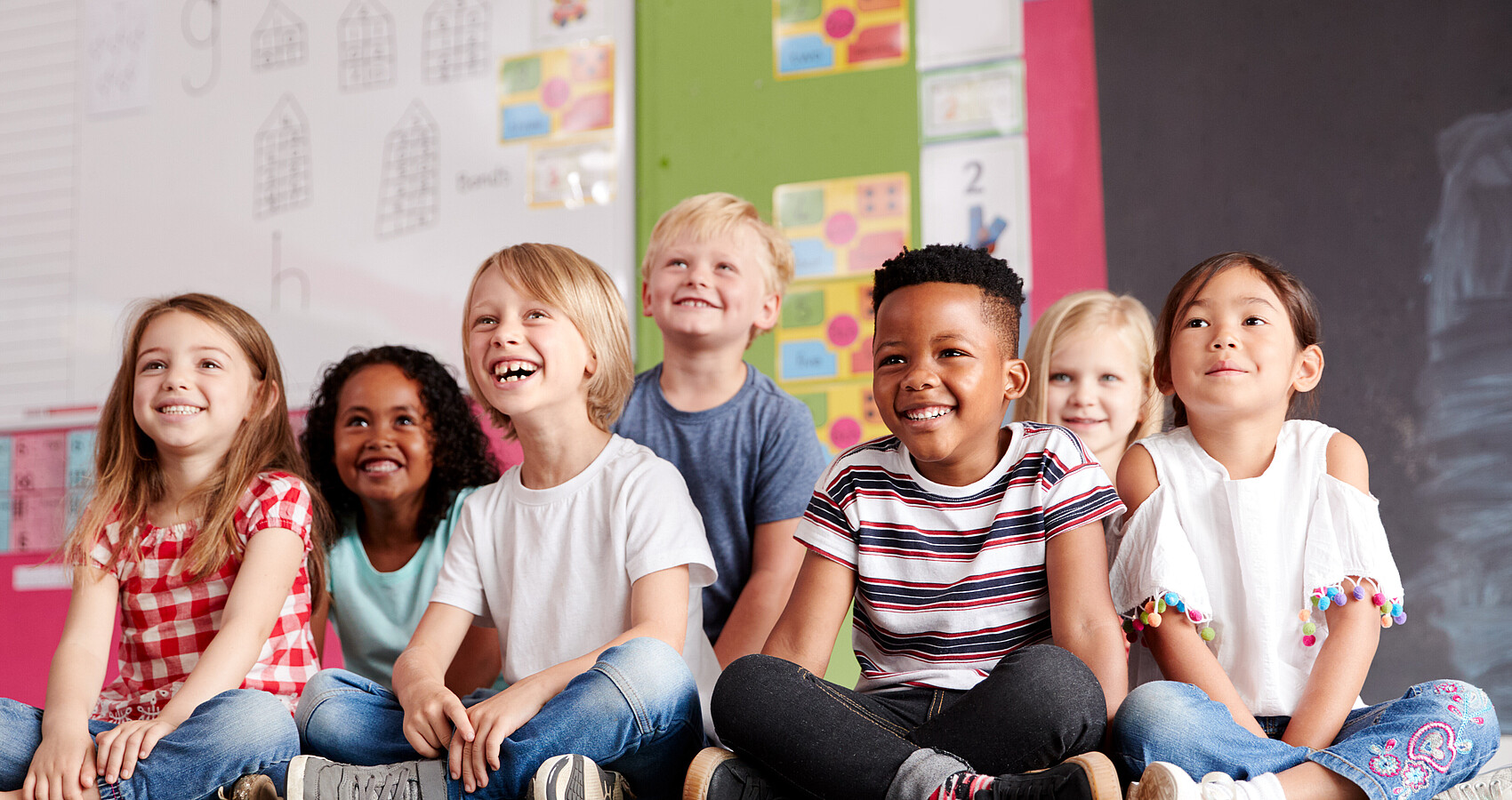 Gruppe von Grundschülern, die auf derm Boden im Klassenzimmer sitzen