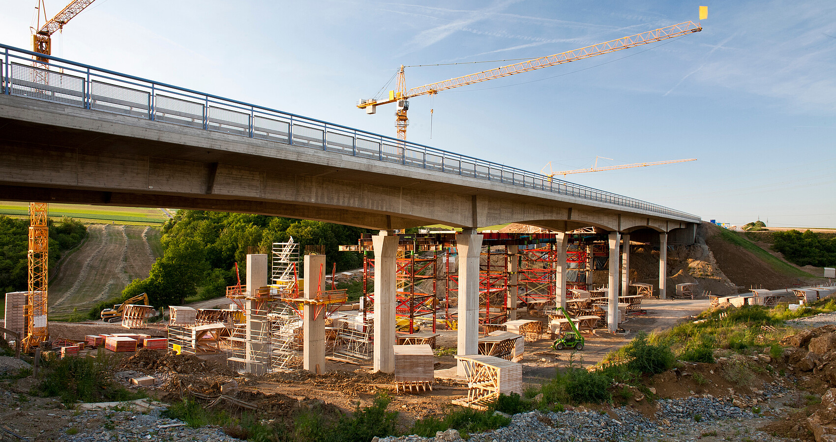 2 Kräne stehen hinter einer Brücke, die saniert werden soll