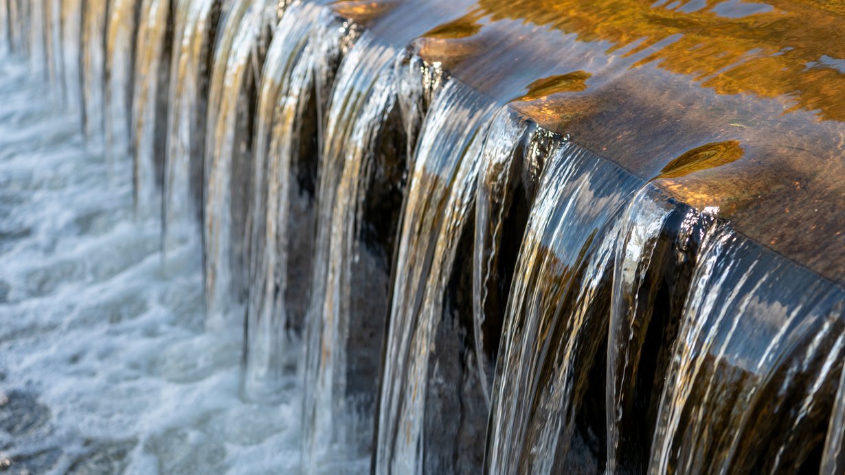 Wasser fällt bei einer Wasserkraftanlage eine kleine Stufe von 50 cm hinunter