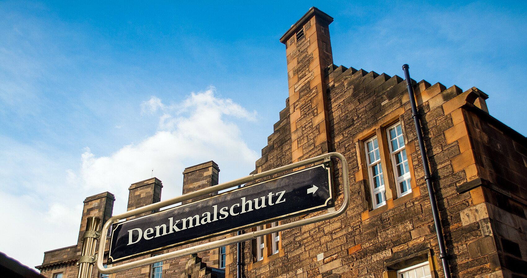Backsteingebäude mit dem Schild "Denkmalschutz" im Vordergrund