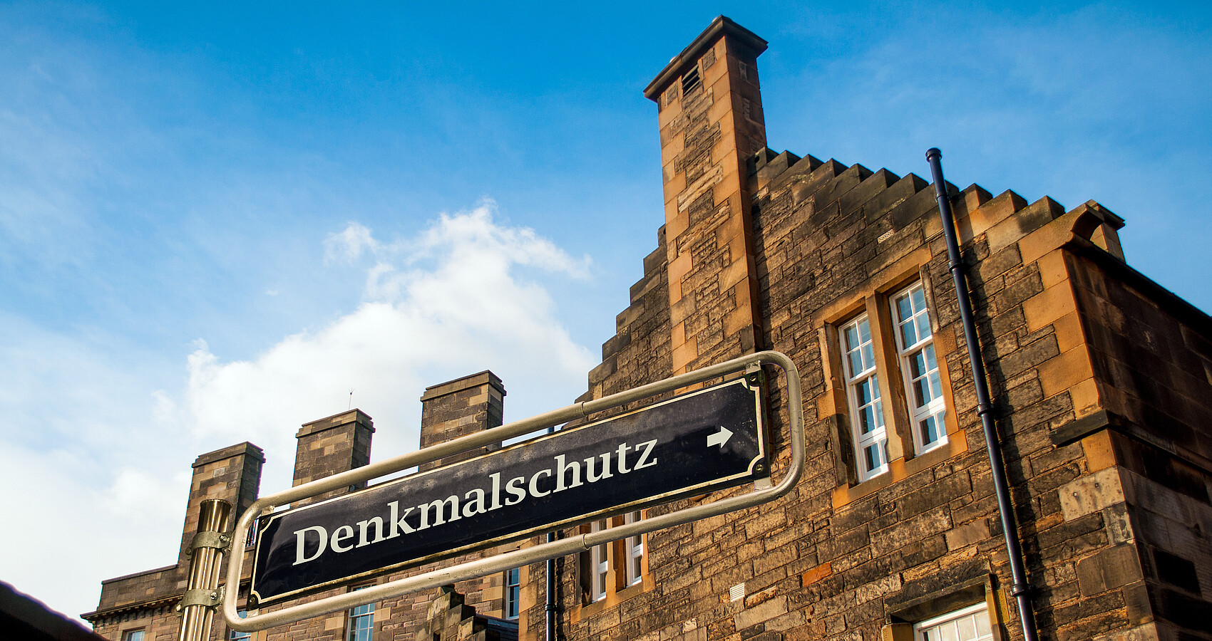 Backsteingebäude mit dem Schild "Denkmalschutz" im Vordergrund