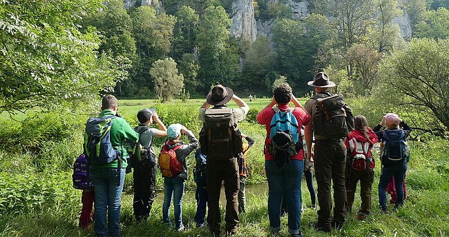 Menschen blicken mit Ferngläsern ins Bisphärengebiet Schwäbische Alb, man sieht die Gruppe von hinten