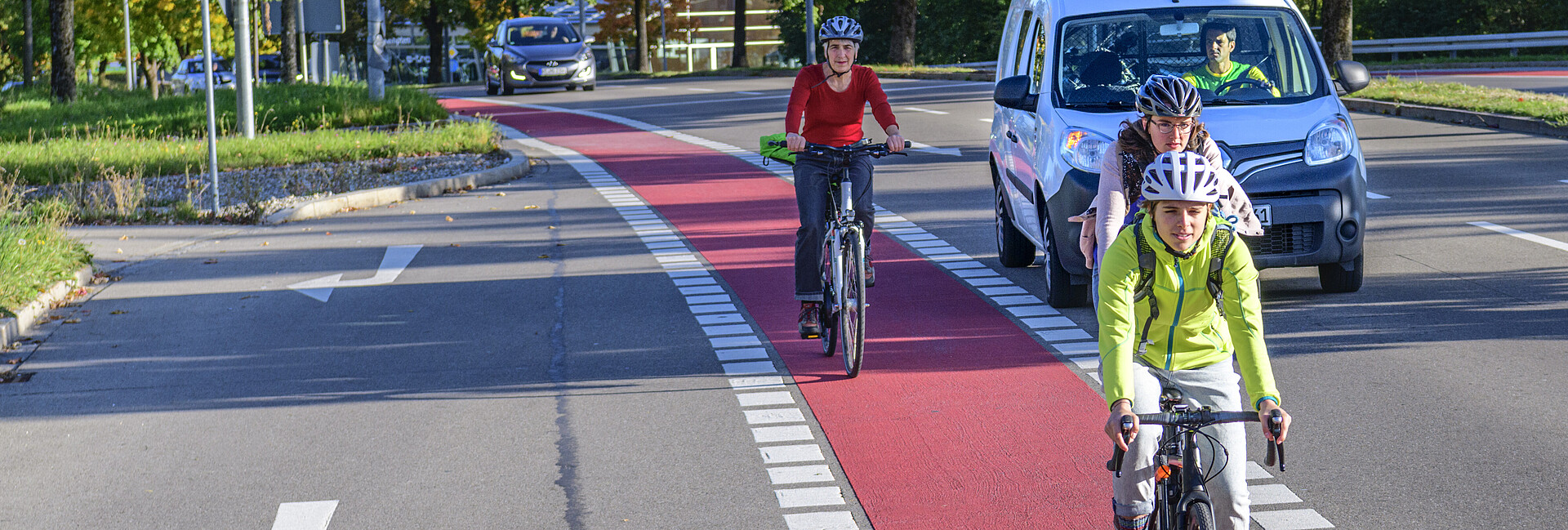 Radfahrer auf einem rot gekennzeichneten Radweg, im Hintergrund ein Auto