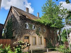 Bild zeigt das Gebäude von der Seite, daneben stehen Bäume