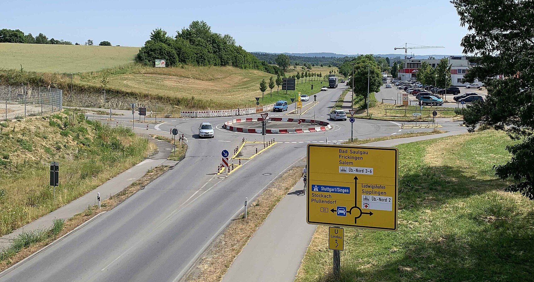 Das Bild zeigt einen befahrenen Kreisverkehrsplatz mit einem Verkehrsschild.
