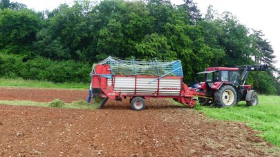Schlepper mit Ladewagen lädt Mahdgut ab