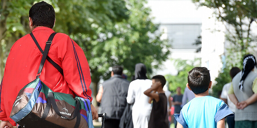Flüchtlinge gehen am 04.08.2014 in der Landeserstaufnahme für Asylbewerber (LEA) in Karlsruhe (Baden-Württemberg) einen Weg entlang.