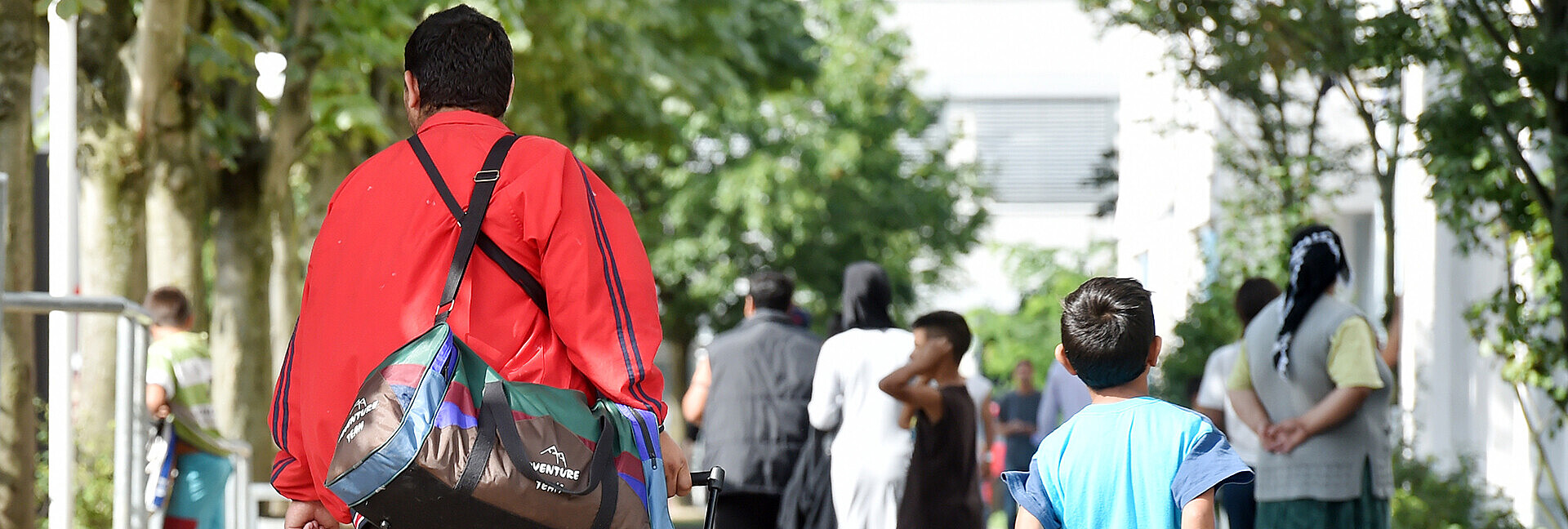 Flüchtlinge gehen am 04.08.2014 in der Landeserstaufnahme für Asylbewerber (LEA) in Karlsruhe (Baden-Württemberg) einen Weg entlang.