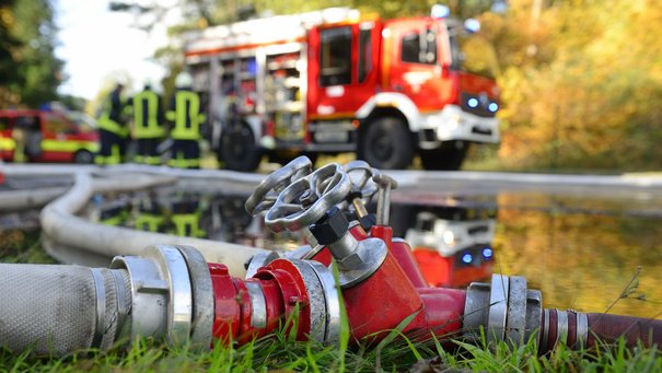 Feuerwehrschlauch, im Hintergrund ein Feuerwehrauto
