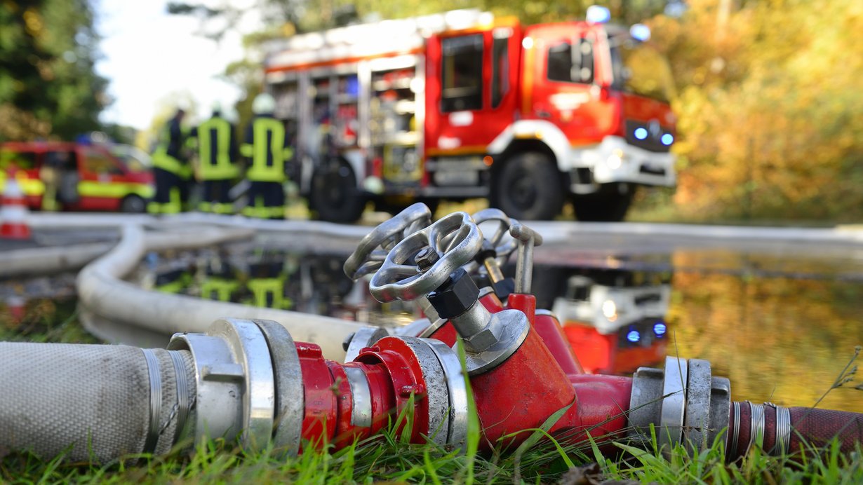 Feuerwehrschlauch, im Hintergrund ein Feuerwehrauto