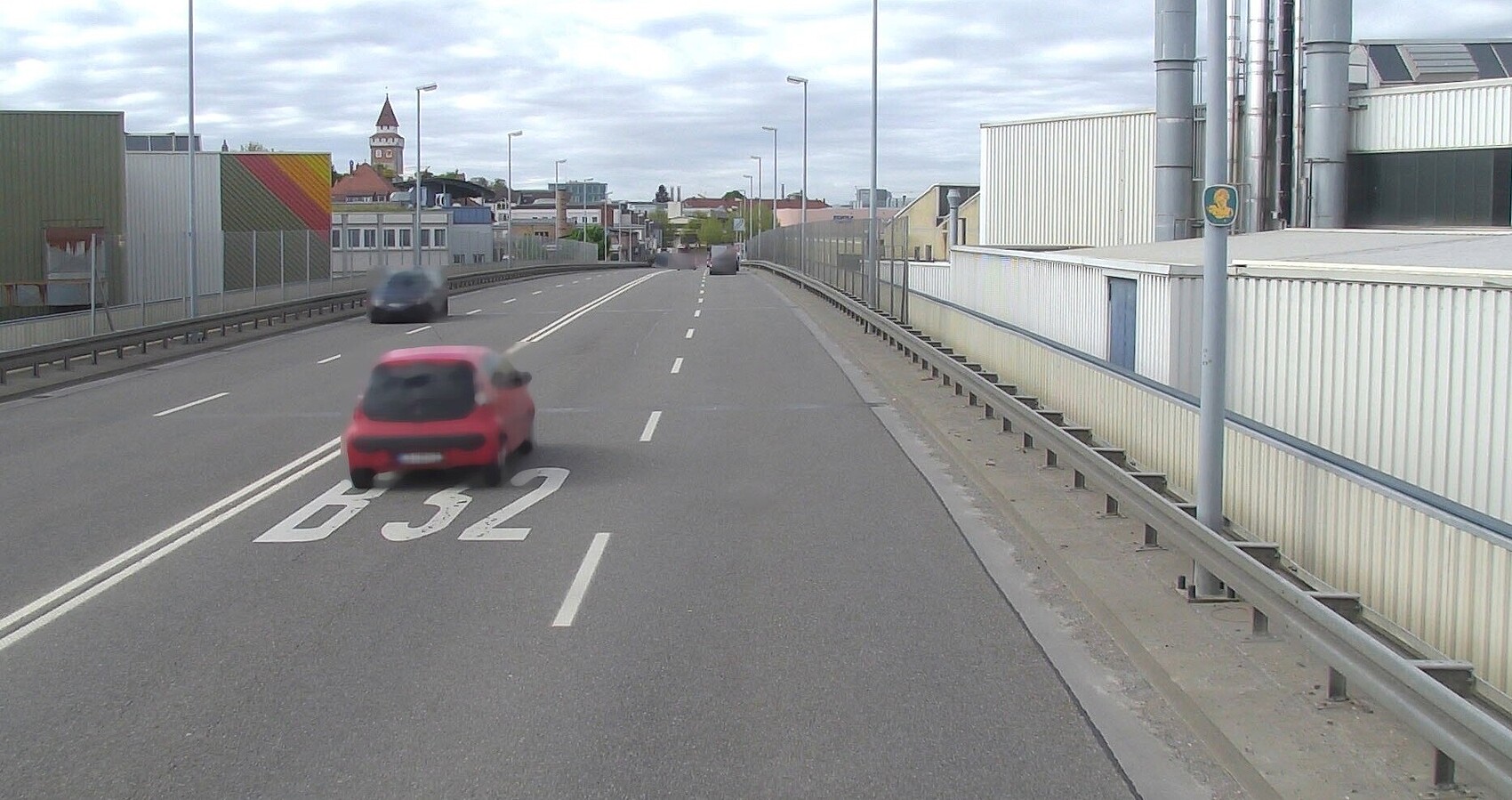 Das Foto zeigt die Nothelferbrücke in Ravensburg. Links und rechts Fabrikgebäude. Im Hintergrund Häuser und eine Kirche