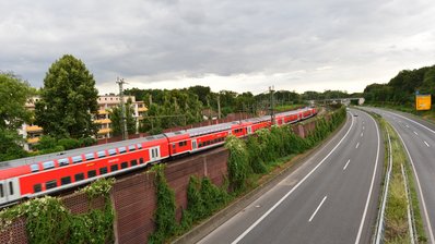 Lärmschutzwand entlang einer Zugstrecke an der gerade ein Regionalexpress vorbeifährt