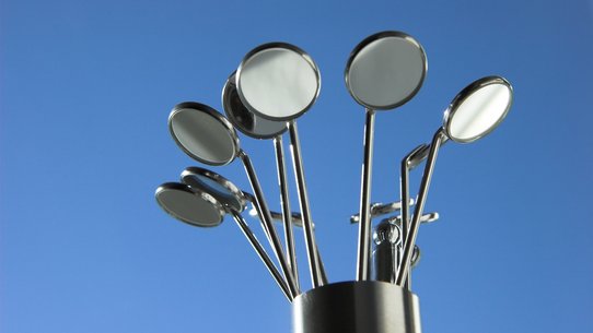 Bild zeigt mehrere Dentalspiegel in einem Behälter vor blauem Hintergrund