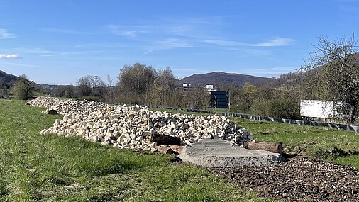 Ein neu angelegtes Habitat für Zauneidechsen, bestehend aus einer Aufschüttung größerer Steine, auf einer Wiese.